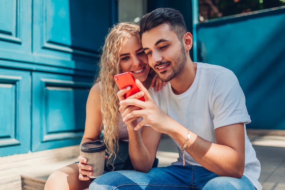 A man and woman looking at an SMS message together.